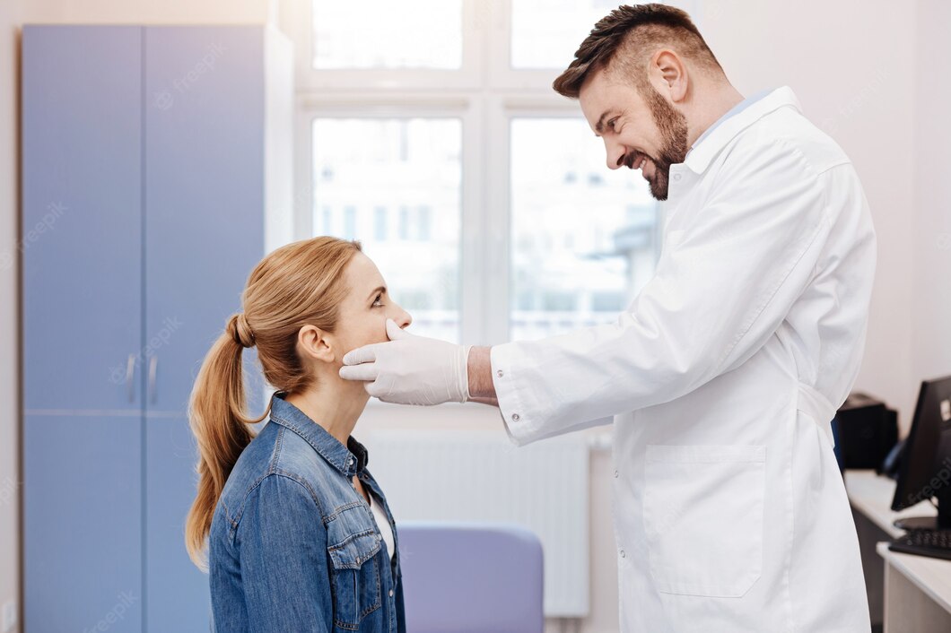 A fül orr gégész megvizsgálja a kék farmer ruhás páciens nyakát